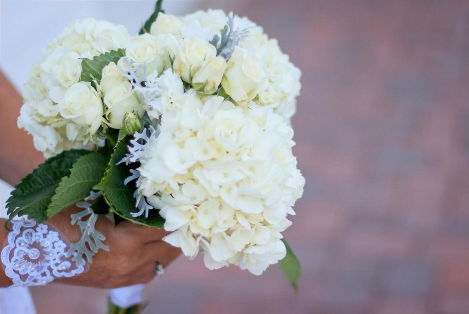 Nahaufnahme eines Arrangements mit Anemonen, Ranunkeln und strukturgebenden Zweigen